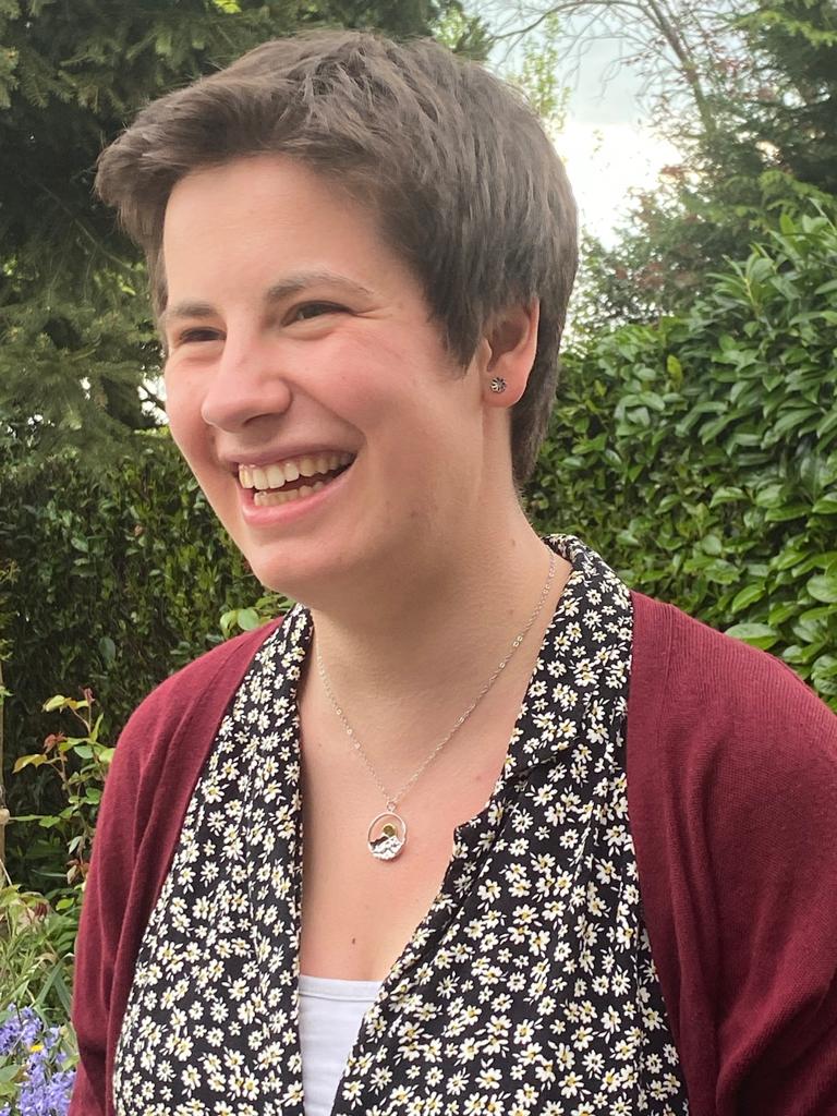 image of Beth Davies, smiling with short brown hair outside with trees