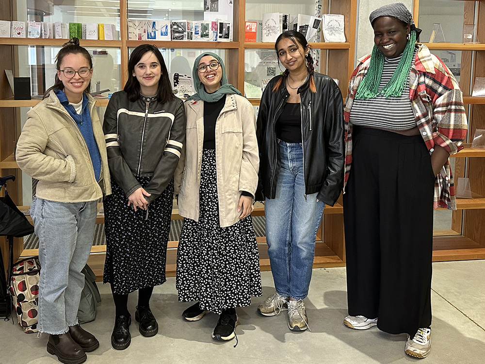 A picture of the four writers and Project Lead Ruth Awolola standing in front of poetry library shelves