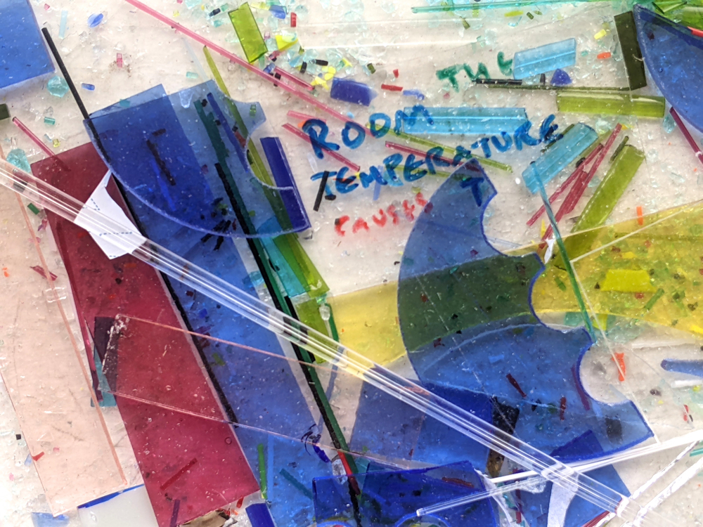 Pieces of coloured glass and written in glass paint the words Room Temperature Causes