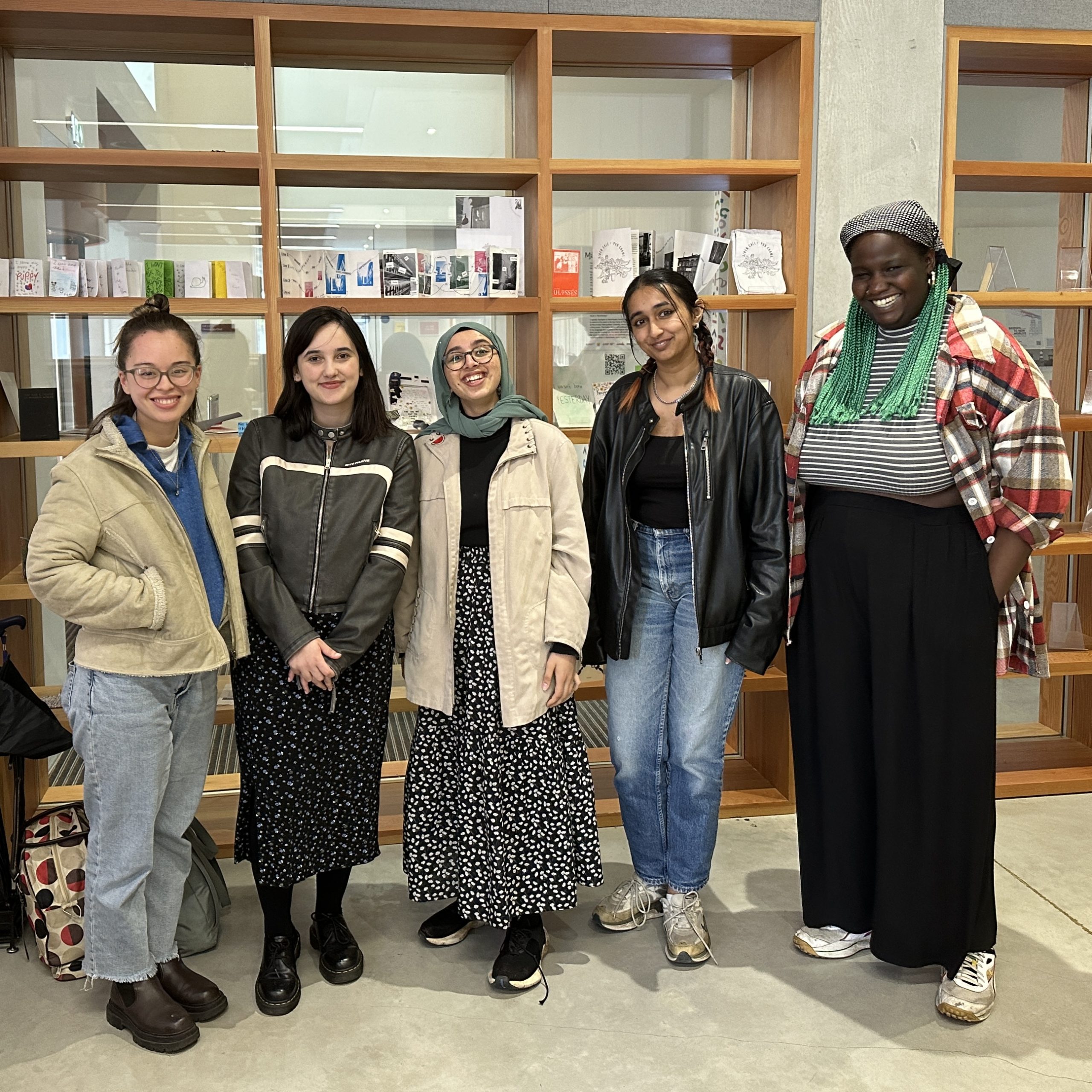 The four writers and Ruth standing in front of shelves at the Manchester Poetry Library, lots of smiles.