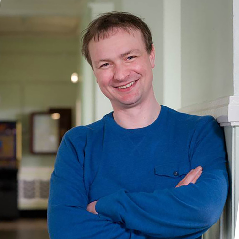 Headshot of stevie Ronnie in a gallery wearing a bright blue crew neck pullover